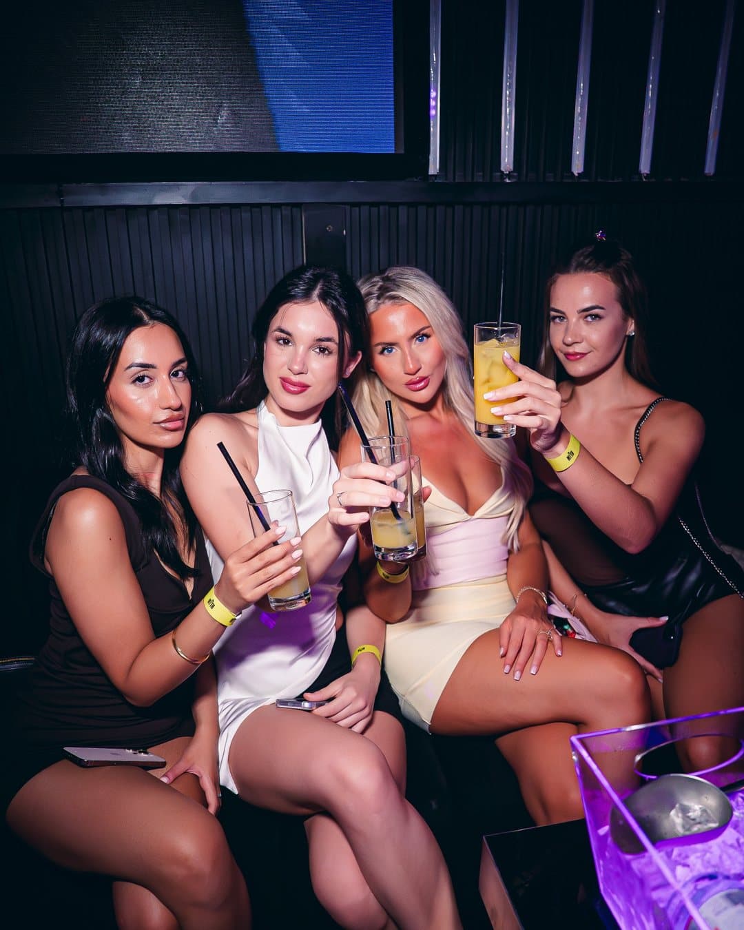 Groups of friends at La Rumba posing with drinks under red and violet club lights